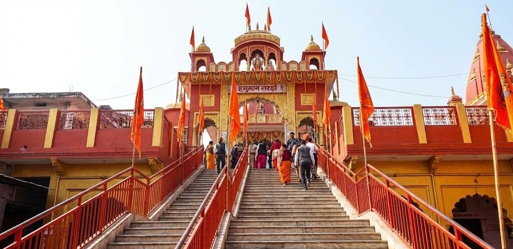 devotees climbing the long flight of stairs to the vibrant red and gold entrance of the hanuman garhi temple in ayodhya.